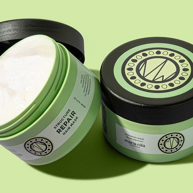 Two jars of Maria Nila Hair Masque, one open to show the cream texture, on a green background.