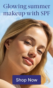 Young, blonde-haired woman smiling and resting her head on her hand.