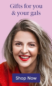 A smiling, middle-aged woman with blonde hair and red lipstick on a pink background with a blue Shop Button.