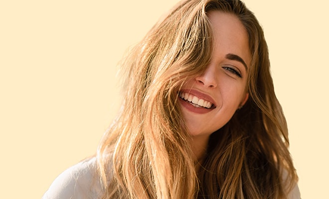 Smiling young woman with hair covering one of her eyes.