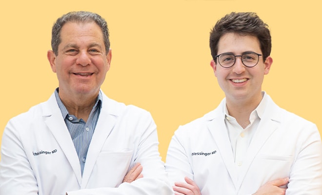 Drs. Joel and Daniel Schlessinger standing together, smiling with their arms crossed.