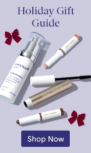 Holiday Gift Guide featuring assorted skin care products including serums and cosmetics on a lavender background with red ribbon bows and a Shop Now button.