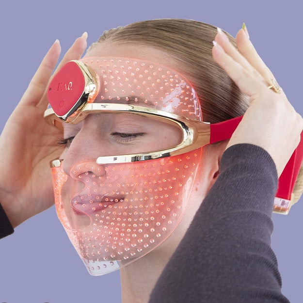 Woman wearing LED light therapy face mask with red lights for skin rejuvenation treatment