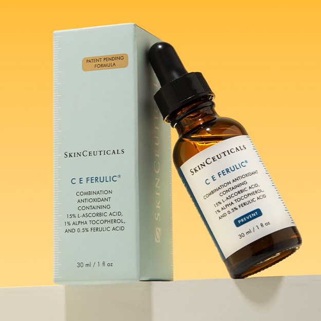 The New Patent-Pending SkinCeuticals C E Ferulic Antioxidant Serum leaning against the box on a yellow background.