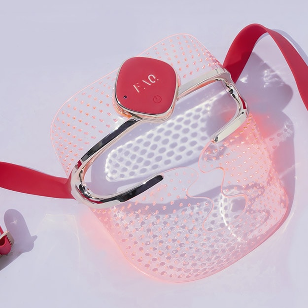 Light purple background featuring a red LED light face mask device.
