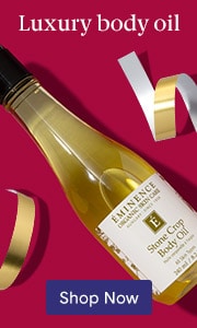 Luxury body oil bottle on burgundy background with gold accents