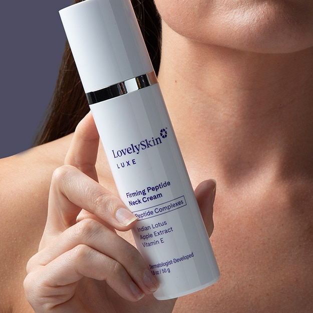 Woman holding LovelySkin LUXE Firming Peptide Neck Cream up to her neck and jawline.