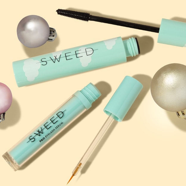 Two open SWEED lash products on cream with silver, pink and gold ornaments.