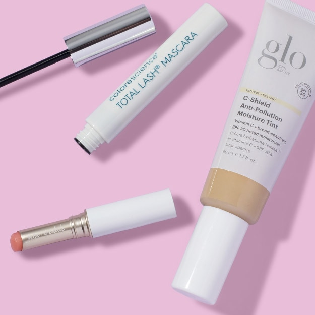 Light pink background featuring colorescience mascara, jane iredale just kissed lip stain, and glo skin beauty tinted moisturizer.