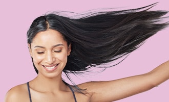 A smiling woman with long, flowing dark hair poses against a purple background.