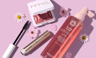 Three skin care products laid flat next to four flowers